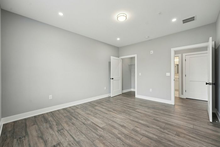 Bright and airy empty bedroom with sleek wood flooring and modern lighting.