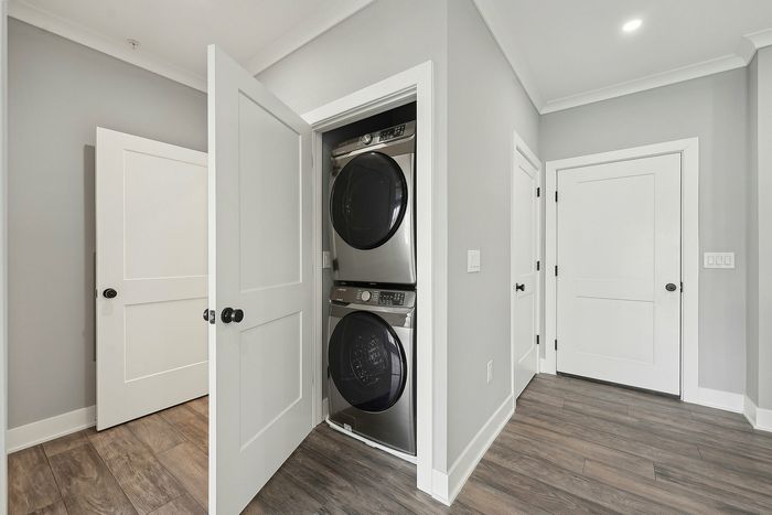 Modern apartment featuring a sleek stackable washer and dryer in a stylish laundry closet, highlighting efficient use of space with elegant doors and contemporary wood flooring.