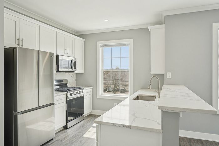 Sleek modern kitchen featuring stainless steel appliances, elegant marble countertops, and sunlit ambiance.