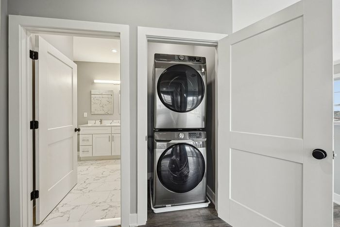 Modern apartment featuring a sleek in-unit washer and dryer adjacent to a stylish bathroom with elegant marble flooring.