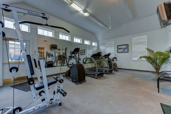 Bright and inviting fitness center with state-of-the-art gym equipment, including treadmills and a multi-functional weight machine.