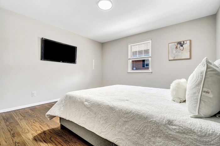 Bright and inviting bedroom with a plush bed, elegant decor, and a modern wall-mounted TV.