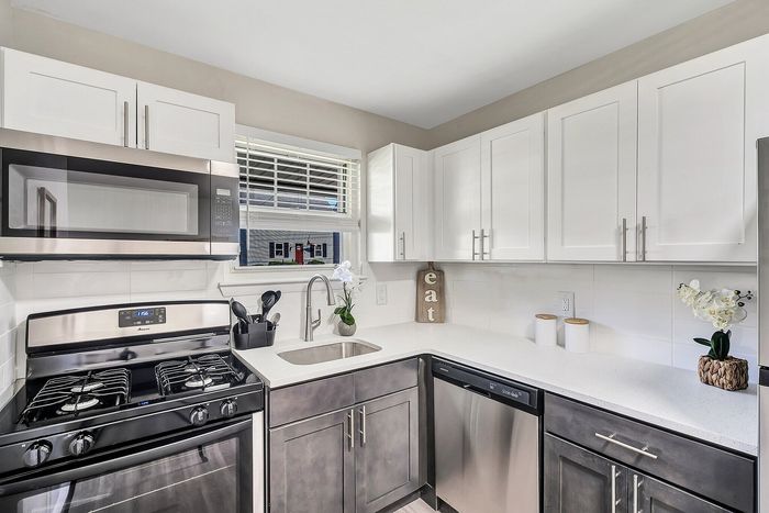 Modern kitchen with sleek stainless steel appliances, elegant white cabinets, and a bright, inviting atmosphere enhanced by natural light.