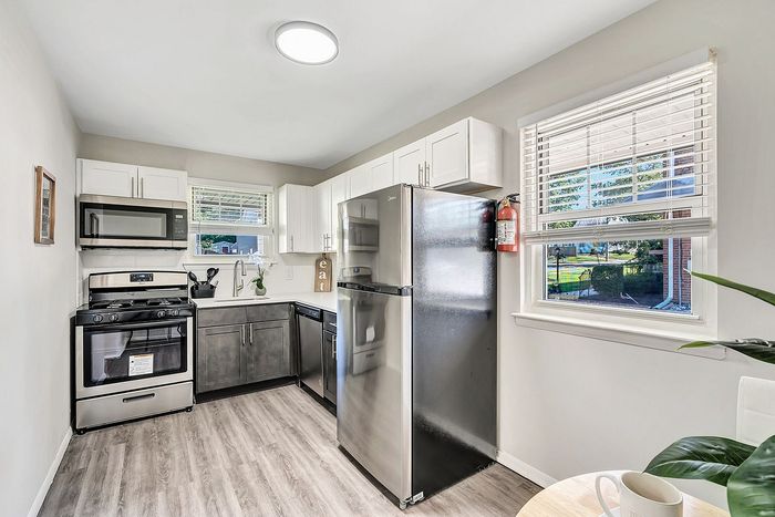 Bright, modern kitchen with sleek stainless steel appliances, elegant cabinetry, and large windows offering natural light.