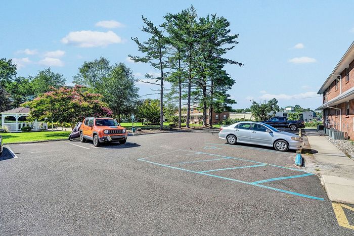 Inviting apartment parking area with well-maintained landscaping and a charming gazebo under a clear blue sky.