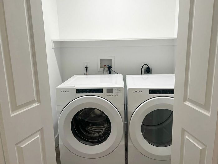 Chic laundry area featuring modern Amana washer and dryer with sleek design in a compact storage space.