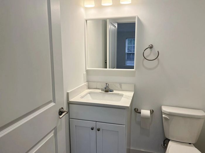 Modern bathroom with sleek white vanity, elegant mirror, and contemporary lighting.