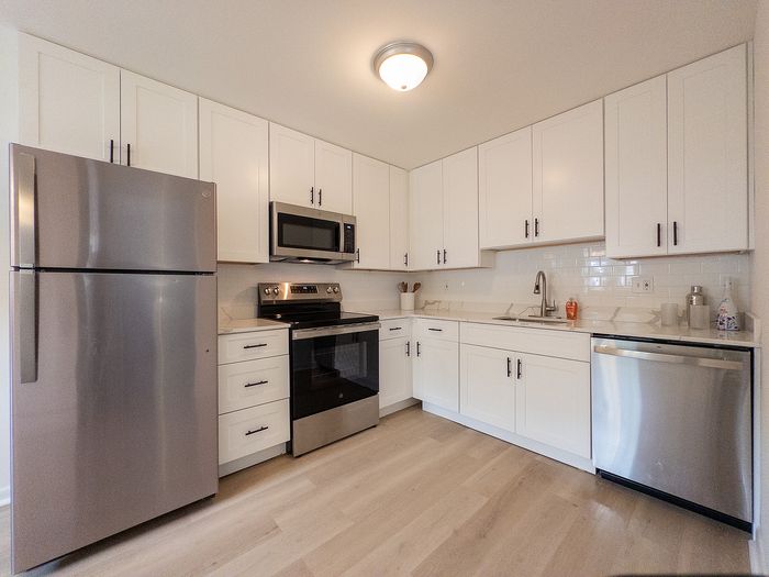Modern kitchen with sleek stainless steel appliances, white cabinetry, and elegant lighting.