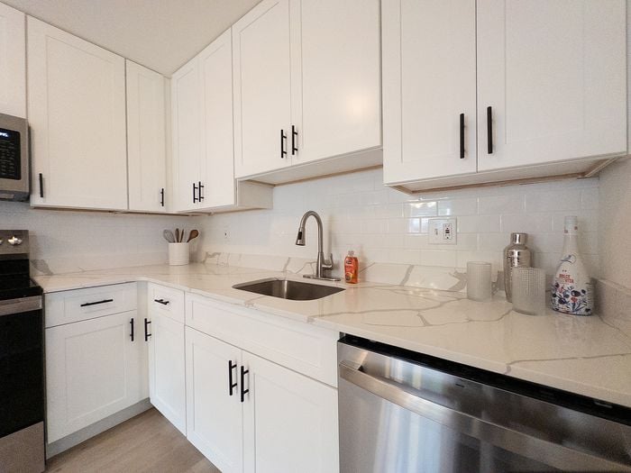 Modern kitchen with sleek white cabinets, marble countertops, and stainless steel appliances.