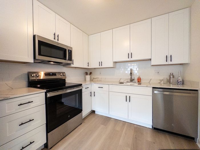 Sleek modern kitchen with stainless steel appliances, elegant white cabinetry, and polished countertops.