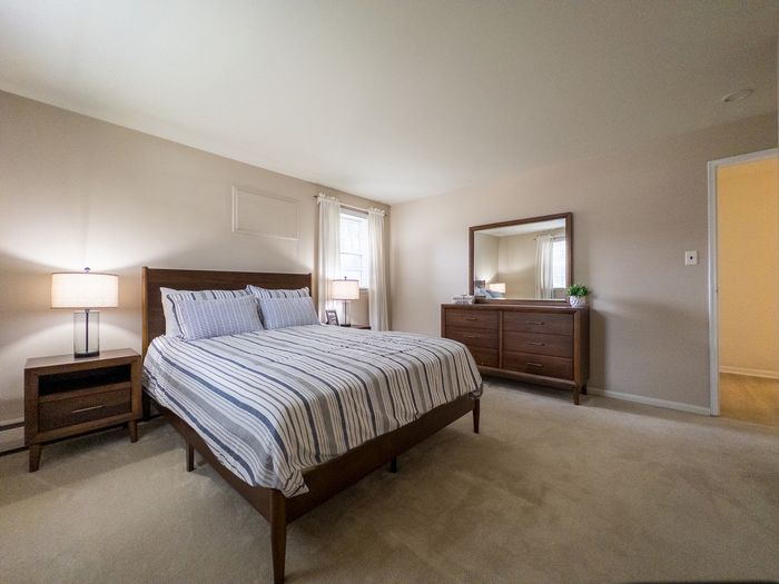 Inviting bedroom with elegant wooden furniture, soft natural light, and calming neutral tones for a cozy retreat.