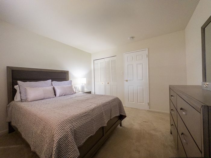 Inviting bedroom with cozy bed, elegant dresser, and soft lighting, perfect for relaxation.