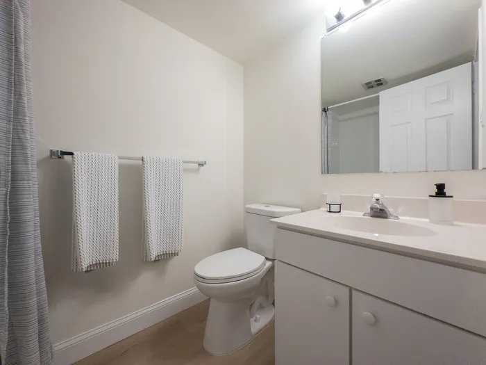 Inviting bathroom with sleek white countertops, modern fixtures, and elegant lighting creating a serene, spa-like atmosphere.