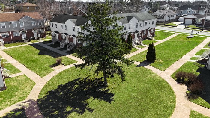 Charming townhouses overlooking a scenic central lawn with mature trees and serene pathways, offering harmonious community living.