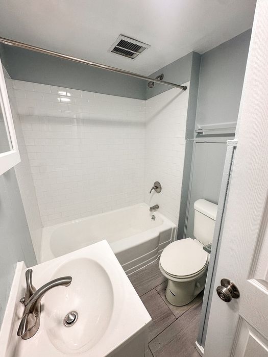 Elegant bathroom featuring a modern white vanity, sleek faucet, classic subway tile bathtub, and soft gray walls for a serene atmosphere.