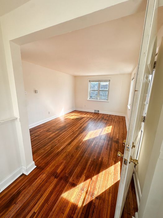 Bright and inviting room with polished hardwood floors and ample natural light, perfect for cozy living.