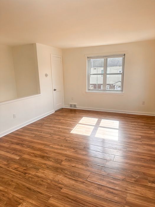 Bright room with elegant hardwood floors and large window allowing natural light to fill the space.