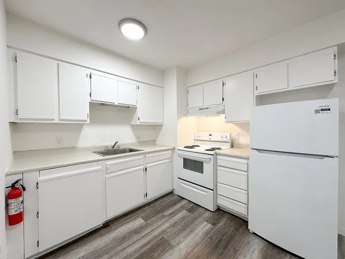 Bright and inviting kitchen with sleek white cabinetry, modern appliances, and elegant wood flooring, perfect for culinary creativity.