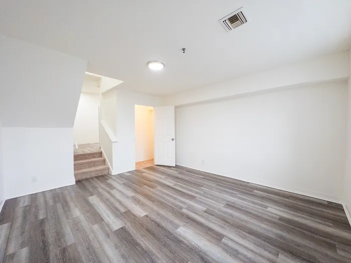 Bright and airy room with elegant wood flooring and a contemporary staircase, ideal for modern living.