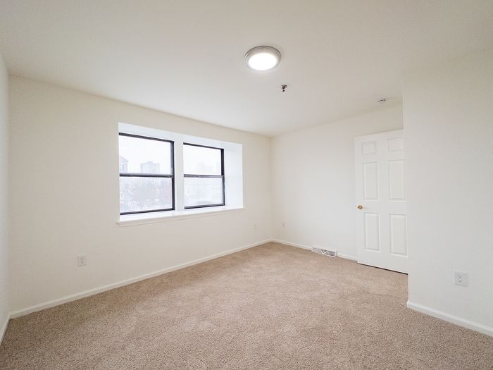Bright and airy bedroom featuring large windows and plush carpeting, perfect for a cozy retreat.