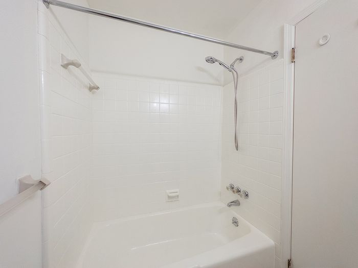 Bright and airy bathroom featuring a modern white tiled bathtub with sleek chrome fixtures.
