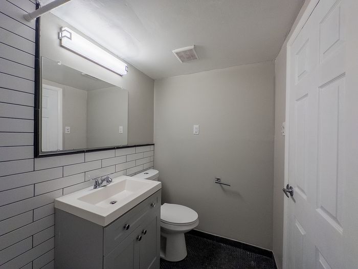 Elegant modern bathroom with sleek tile design, a large mirror, and stylish vanity creating a refreshing ambiance.