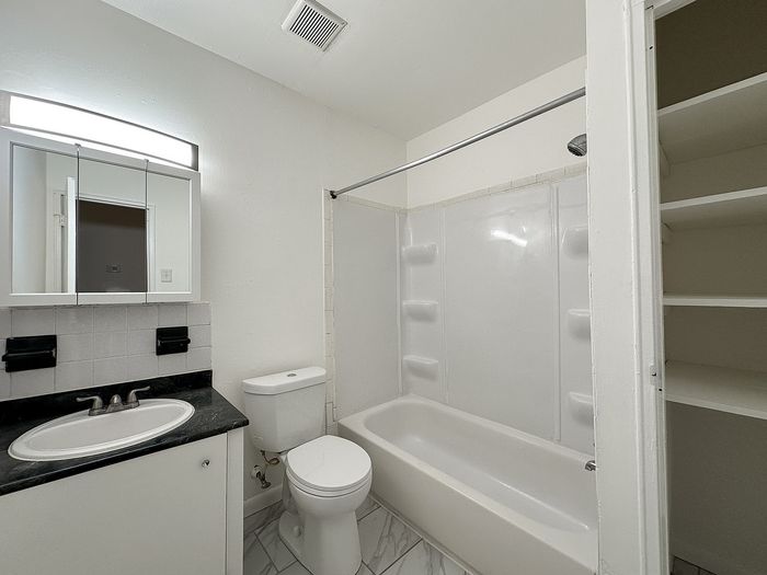 Bathroom with tub/shower, vanity, toilet, and linen closet.