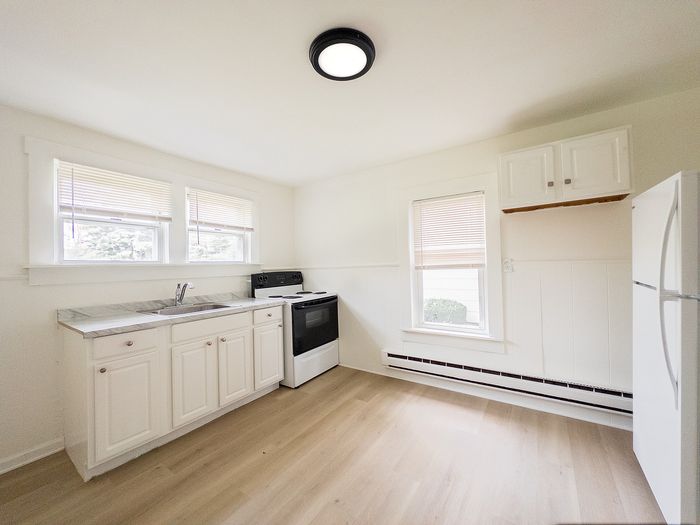 Bright and inviting kitchen with modern white cabinetry, sleek countertops, and large windows providing ample natural light.
