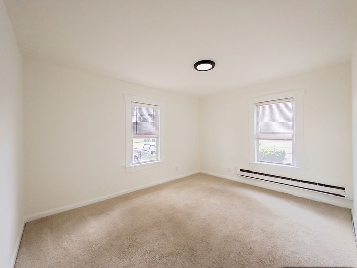 Bright, cozy room with soft carpeting and large windows offering natural light, perfect for relaxation.