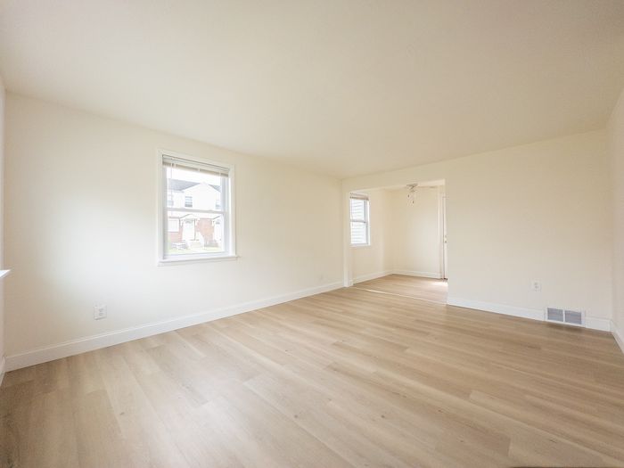 Bright and airy living room with elegant hardwood floors and large windows, offering abundant natural light.