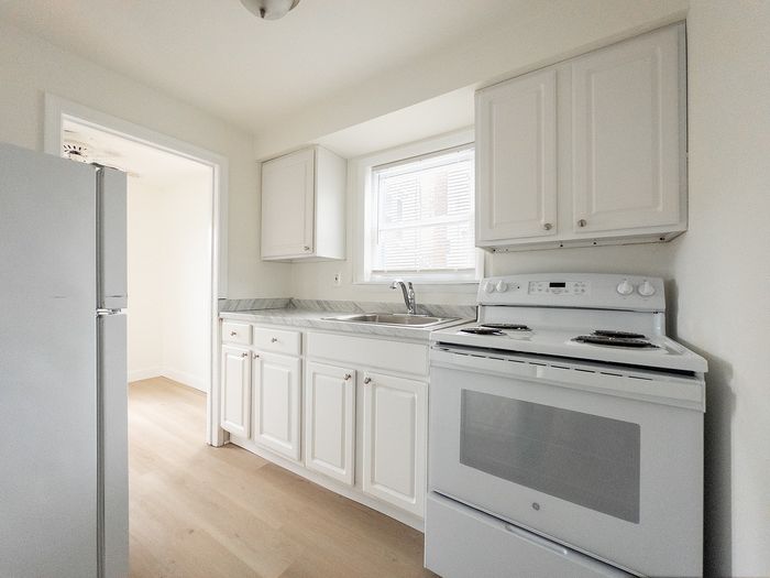 Bright and modern kitchen with sleek white cabinetry, spacious countertops, and an electric stove, perfect for culinary enthusiasts.