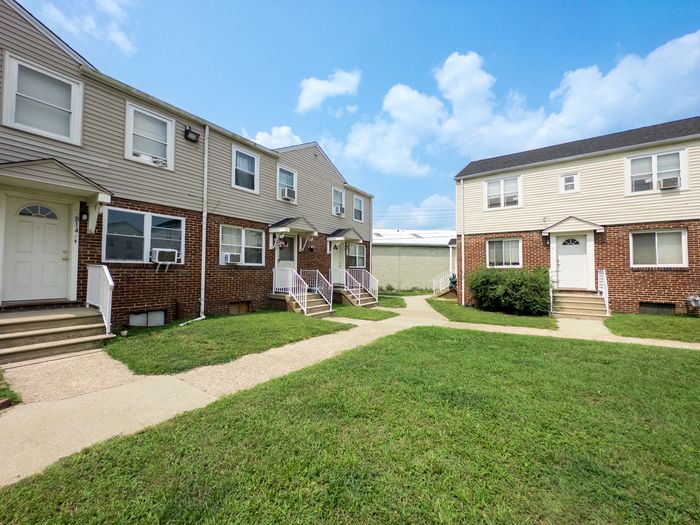 Charming apartment complex showcasing classic brick facades, manicured lawns, and a bright sunny sky.