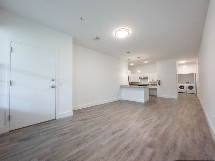 Modern open-concept apartment with sleek wood flooring, spacious kitchen with granite countertops, and in-unit laundry facilities.