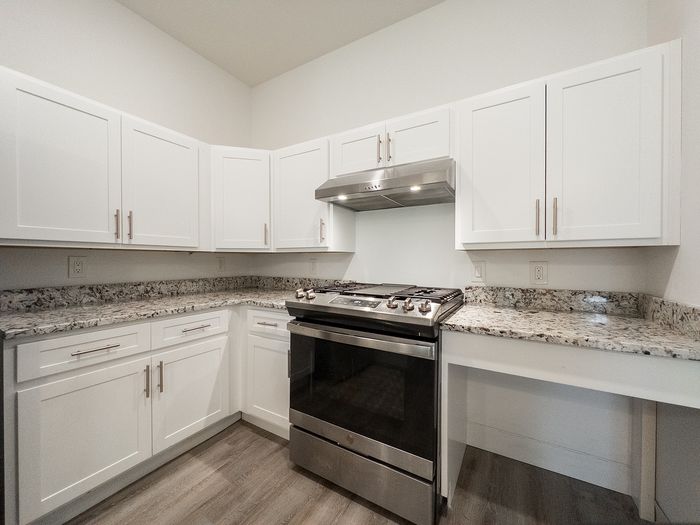 Modern kitchen with sleek stainless steel appliances, elegant granite countertops, and stylish white cabinetry.