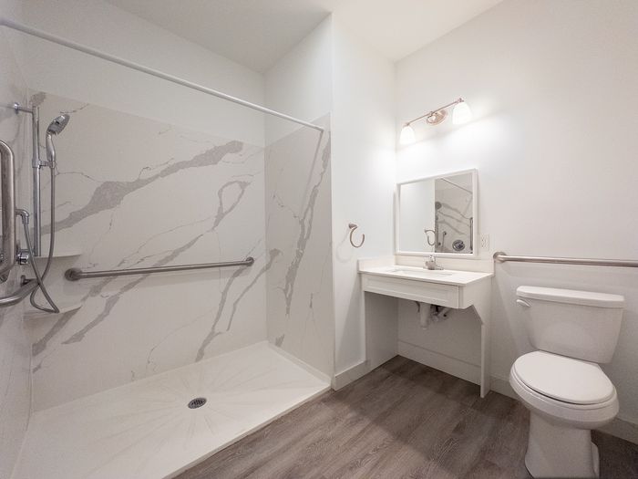 Contemporary bathroom design with elegant marble-patterned shower, sleek vanity, and accessible features.