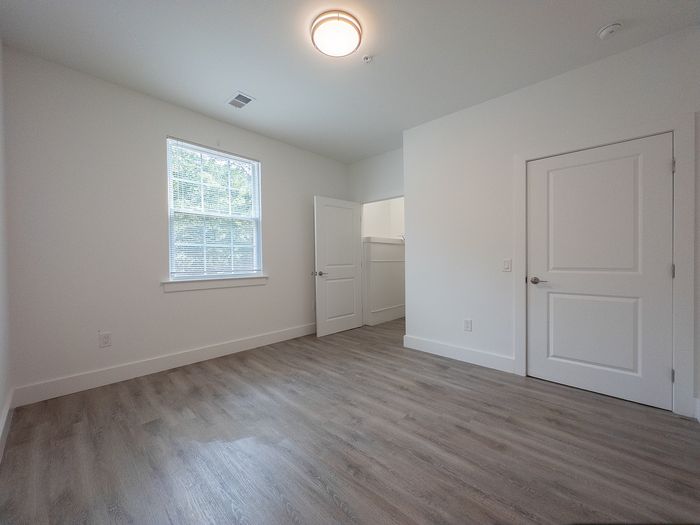 Bright and spacious room with elegant wood flooring and abundant natural light from large window.