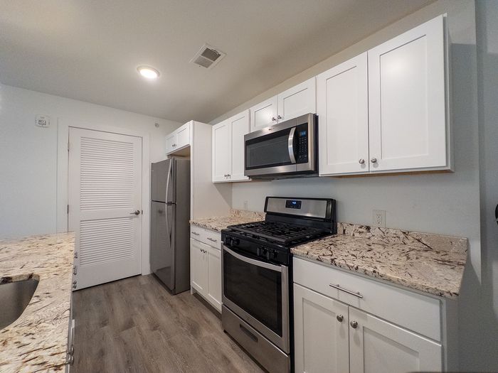 Modern kitchen with sleek stainless steel appliances, elegant granite countertops, and ample white cabinetry.