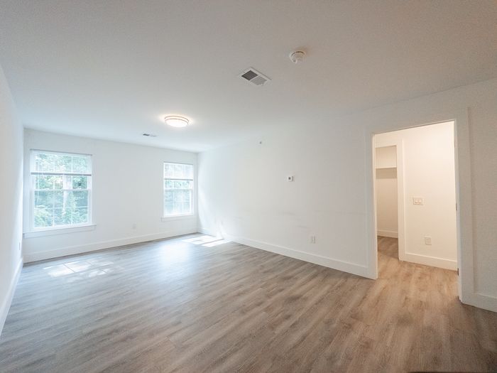 Bright and spacious empty room with elegant hardwood floors and large windows, ideal for customization.