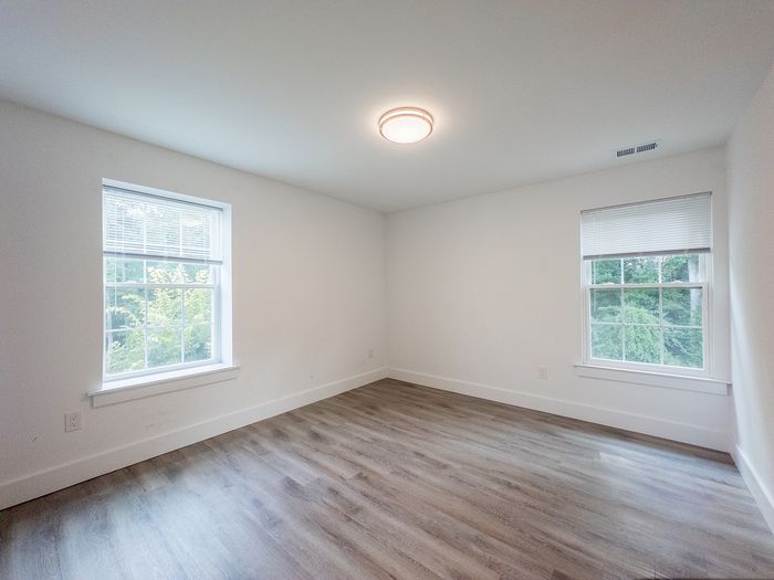 Bright and spacious bedroom with large windows, modern wood flooring, and soft natural light.