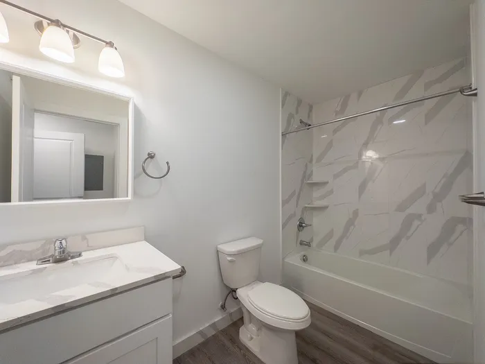 Modern bathroom featuring elegant marble-patterned tiles and sleek vanity with ample lighting.