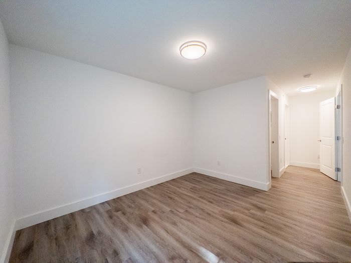 Bright and spacious empty room with sleek wood flooring and modern ceiling lights, perfect for creative design ideas.