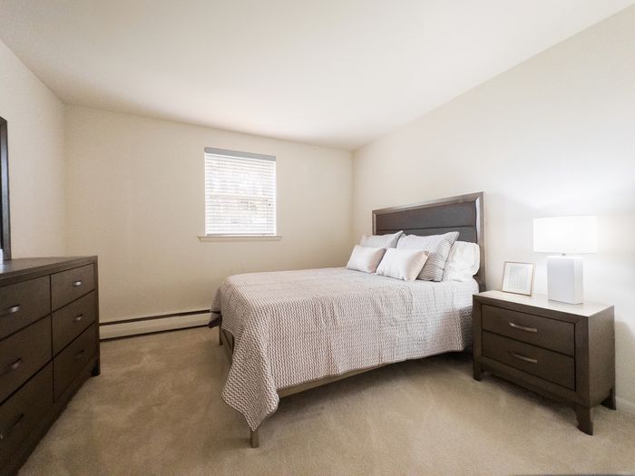 Bedroom with queen bed, nightstand and dresser at College Arms Apartments in Collegeville, PA.