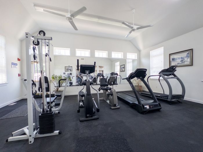 Fitness room at College Arms Apartments in Collegeville, PA with treadmills, exercise bikes, weight machine, and a mirror.