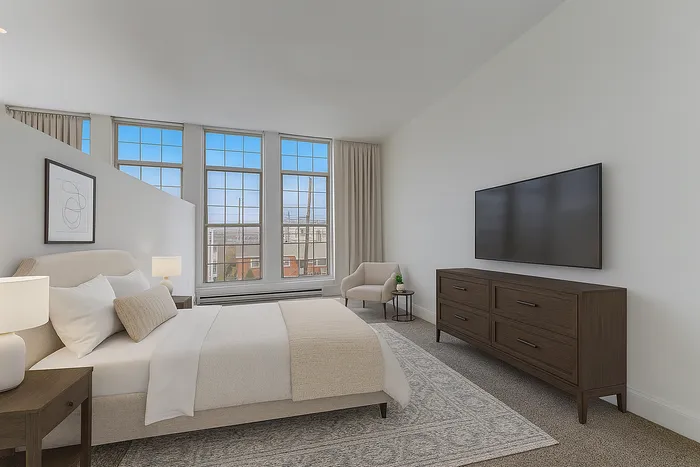 Bright furnished bedroom at Franklin Manor Apartments in West Reading, PA with queen bed, nightstands, and large windows.
