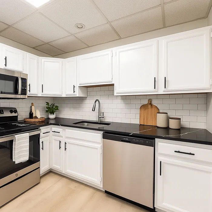 Kitchen at Franklin Manor Apartments with white cabinets, black counters and stainless appliances.