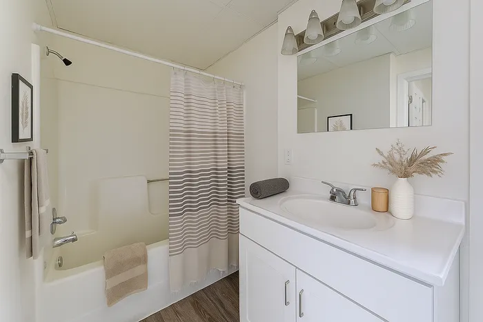 Elegant bathroom with modern fixtures, featuring a bathtub with a striped curtain, sleek white vanity, and stylish decor accents.