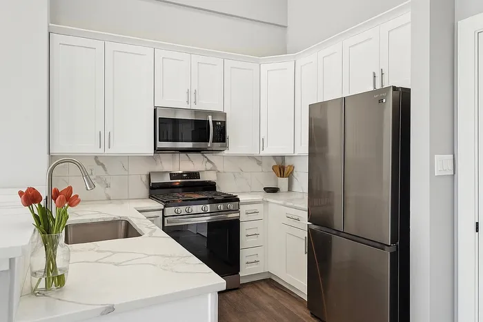 Modern kitchen with sleek stainless steel appliances, elegant white cabinetry, and a polished marble countertop adorned with fresh tulips.