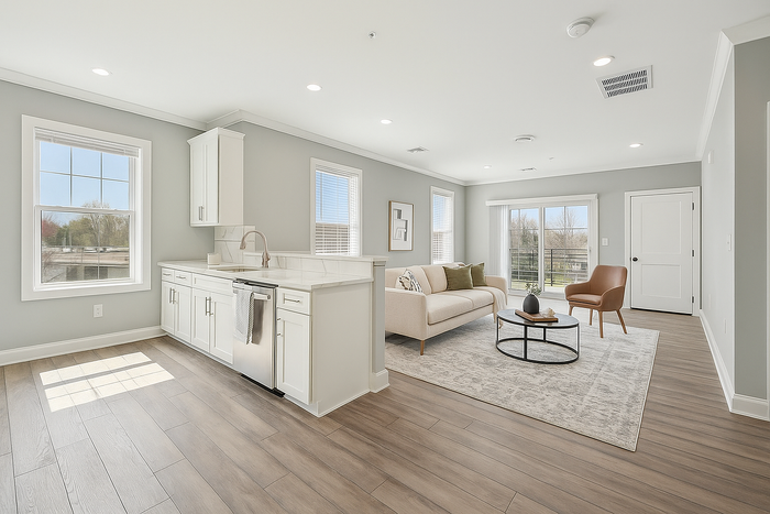 Bright and modern open-concept living space featuring elegant hardwood floors, a chic kitchen with white cabinetry, and a cozy living area with stylish furniture and large windows.