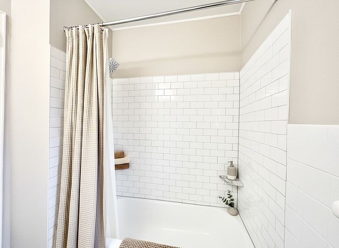 Modern bathroom with elegant white subway tiles and a cozy shower curtain for a fresh, inviting ambiance.