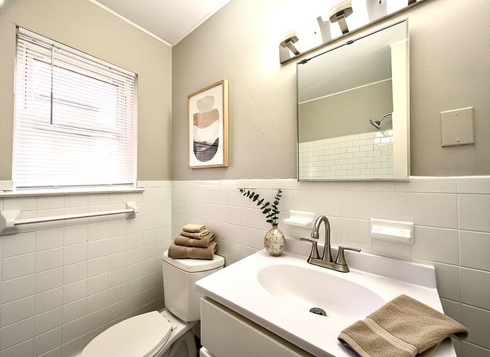 Bright and elegant bathroom featuring a modern sink, decorative artwork, and stylish lighting.
